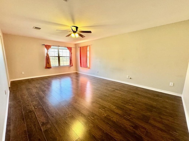 empty room with a ceiling fan, baseboards, dark wood-style floors, and visible vents