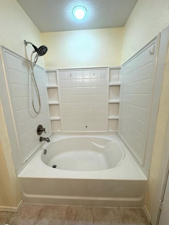 bathroom featuring a textured ceiling, tile patterned flooring, and a textured wall