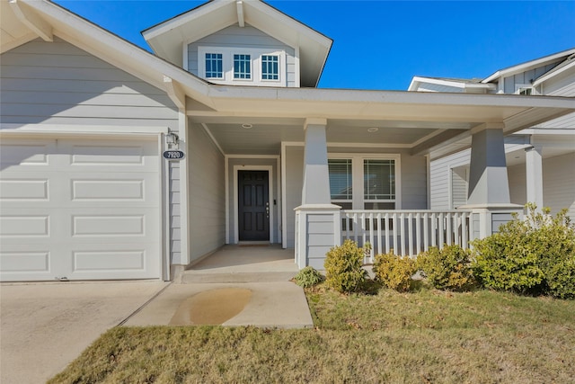 view of exterior entry featuring a garage, a porch, and a yard