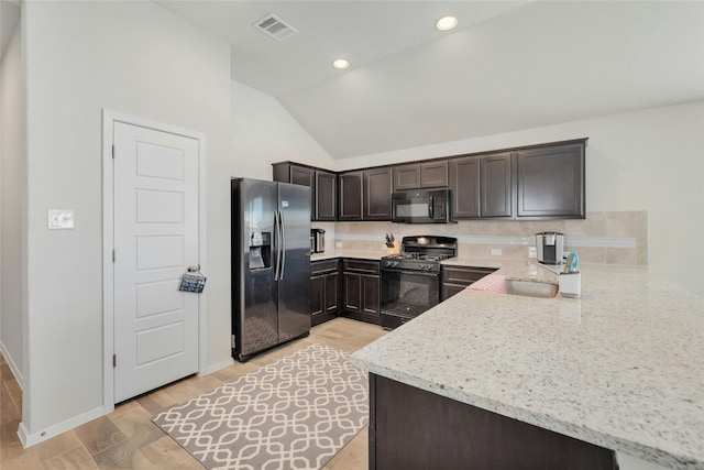 kitchen featuring dark brown cabinetry, sink, kitchen peninsula, light stone countertops, and black appliances