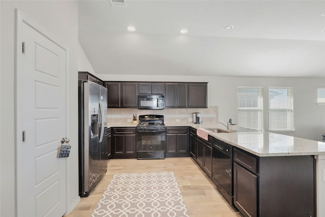 kitchen with tasteful backsplash, black appliances, sink, light hardwood / wood-style floors, and kitchen peninsula