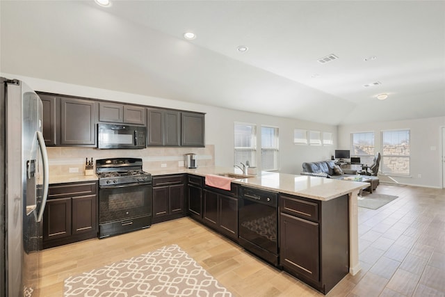 kitchen with vaulted ceiling, black appliances, kitchen peninsula, and plenty of natural light