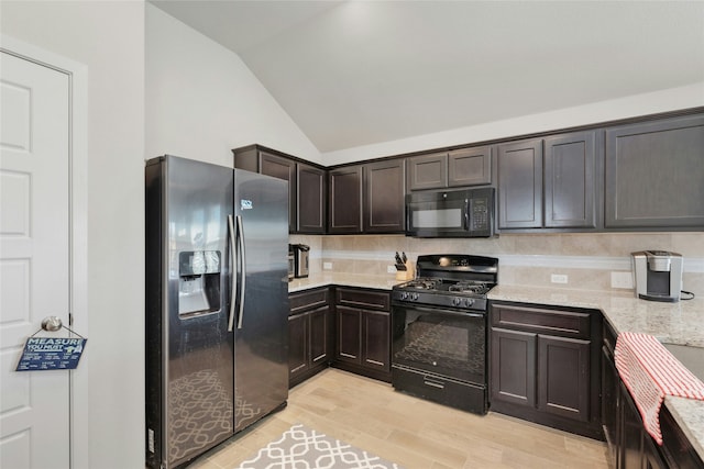 kitchen with dark brown cabinets, light stone countertops, black appliances, decorative backsplash, and vaulted ceiling