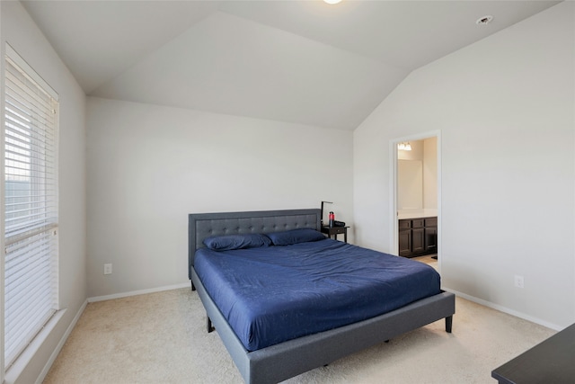 bedroom featuring vaulted ceiling, light carpet, and connected bathroom