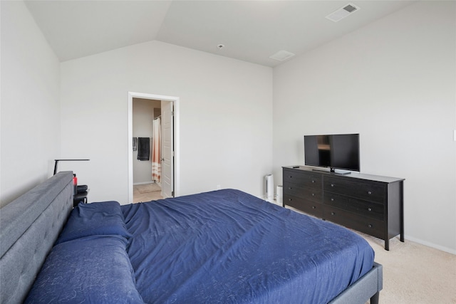 bedroom with lofted ceiling, ensuite bathroom, and light colored carpet