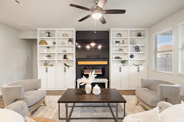 living room with ceiling fan, a large fireplace, and light wood-type flooring