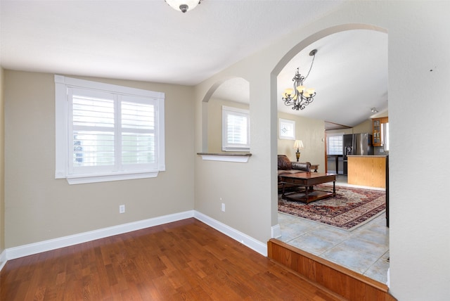 interior space with lofted ceiling, hardwood / wood-style floors, and a notable chandelier