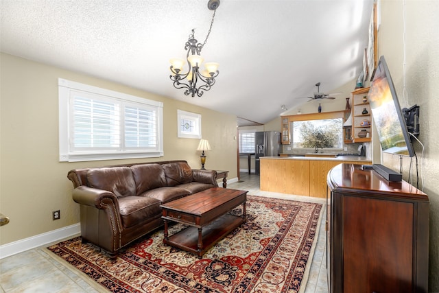 living room featuring lofted ceiling, sink, and ceiling fan with notable chandelier