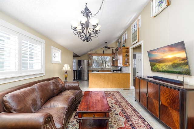 living room featuring ceiling fan with notable chandelier, vaulted ceiling, and light tile patterned floors