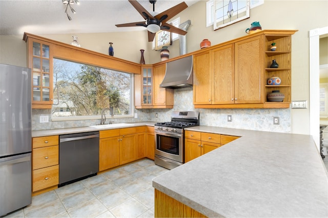 kitchen featuring lofted ceiling, wall chimney range hood, sink, stainless steel appliances, and tasteful backsplash