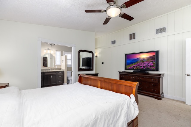 carpeted bedroom featuring sink, connected bathroom, a textured ceiling, and ceiling fan