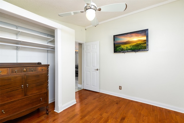 unfurnished bedroom with wood-type flooring, ornamental molding, ceiling fan, a textured ceiling, and a closet