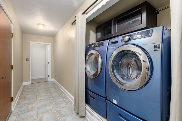 clothes washing area with light tile patterned floors and a textured ceiling