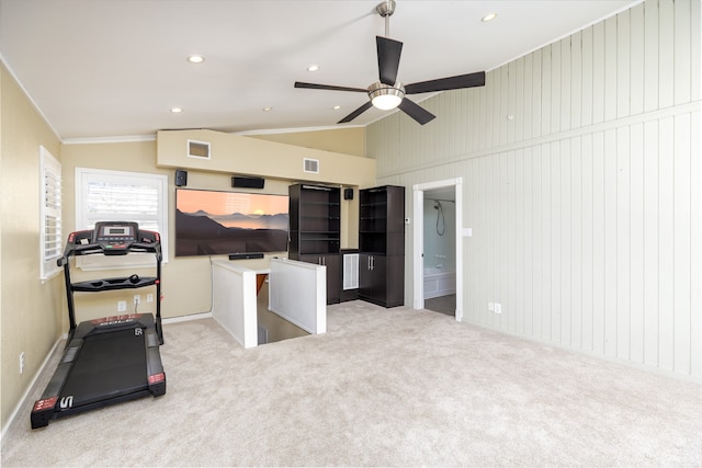 workout room featuring vaulted ceiling, light carpet, ceiling fan, and wood walls