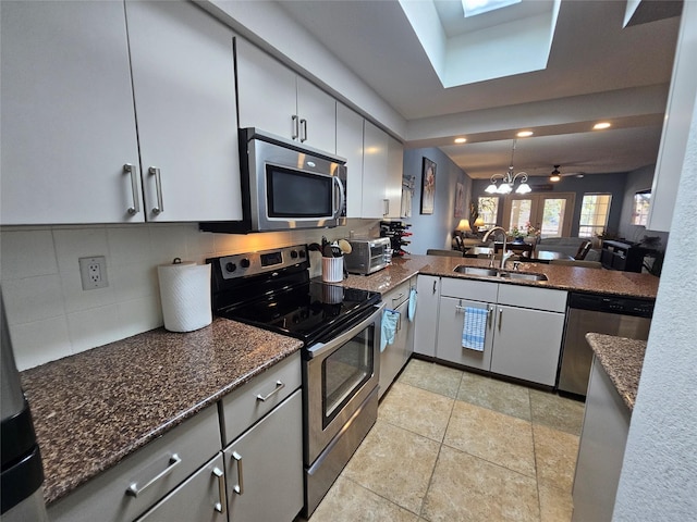 kitchen featuring appliances with stainless steel finishes, tasteful backsplash, sink, a notable chandelier, and kitchen peninsula