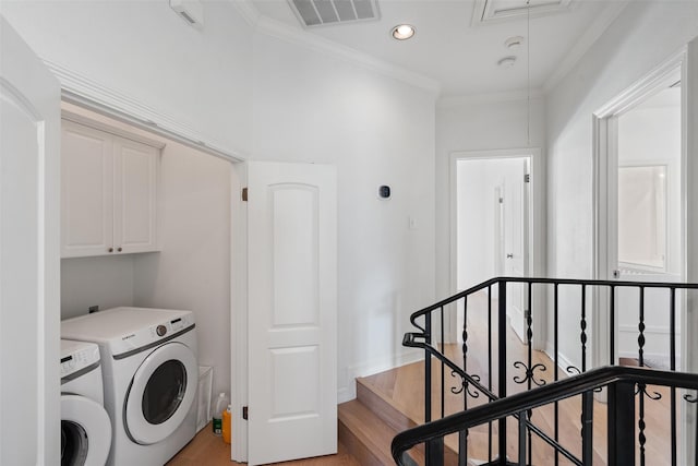 laundry area with crown molding, cabinets, washing machine and dryer, and light wood-type flooring