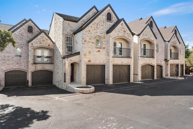 1701 Spyglass Dr Unit 11, Austin, TX 78746 - french country style house with an attached garage, driveway, a balcony, and stone siding