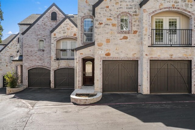 1701 Spyglass Dr Unit 11, Austin, TX 78746 - french country style house featuring a garage, stone siding, a balcony, and driveway