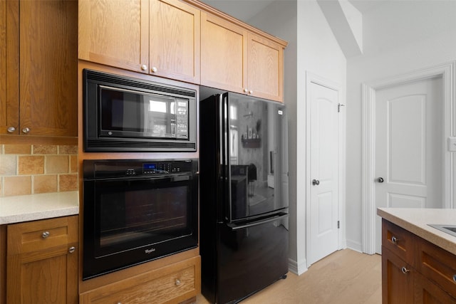 kitchen featuring backsplash, light brown cabinets, and black appliances