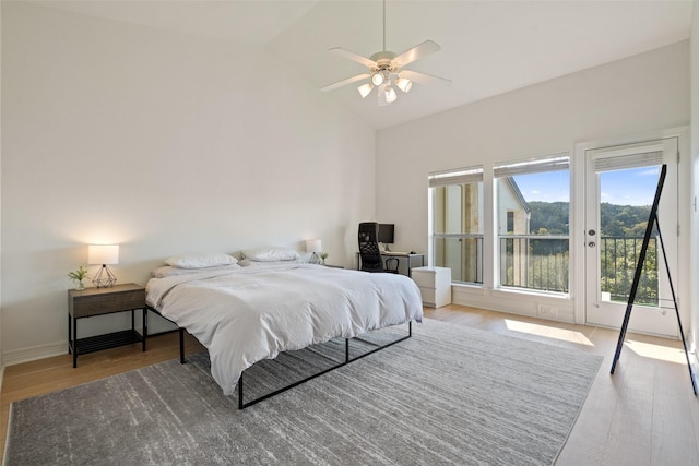 bedroom with ceiling fan, wood-type flooring, access to exterior, and vaulted ceiling