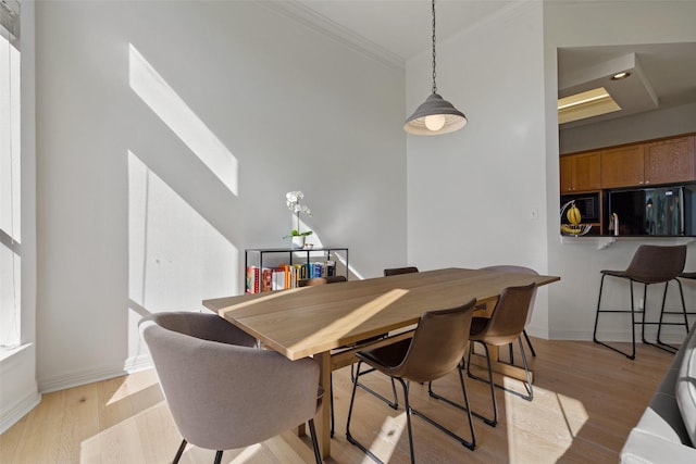 dining room with ornamental molding and light hardwood / wood-style flooring