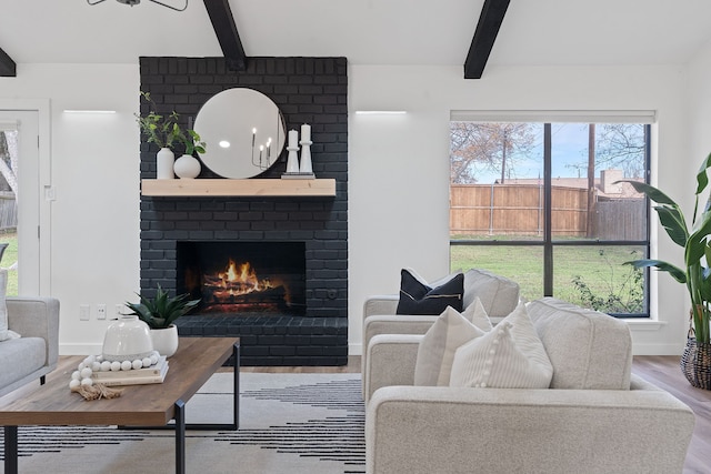 living room featuring beamed ceiling, wood-type flooring, and a fireplace