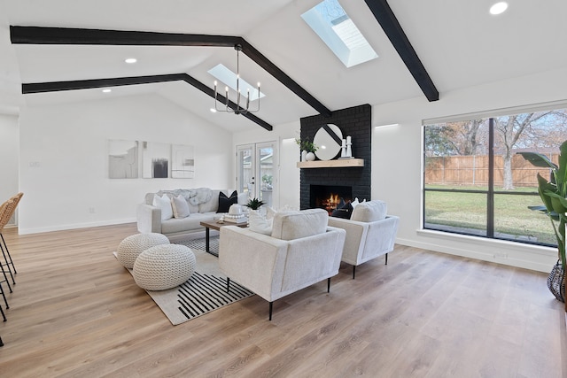 living room with a fireplace, beam ceiling, a chandelier, and light hardwood / wood-style floors