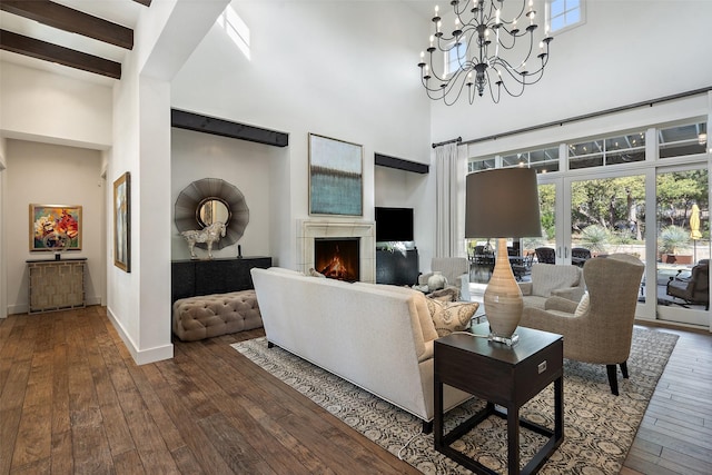 living room featuring beamed ceiling, wood-type flooring, a towering ceiling, and a chandelier