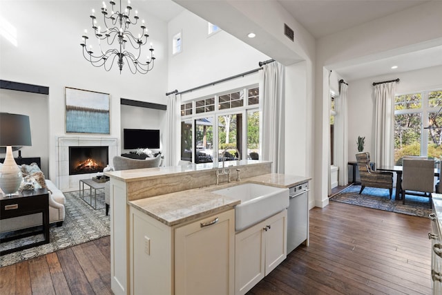 kitchen with a kitchen island, dishwasher, sink, hanging light fixtures, and light stone counters