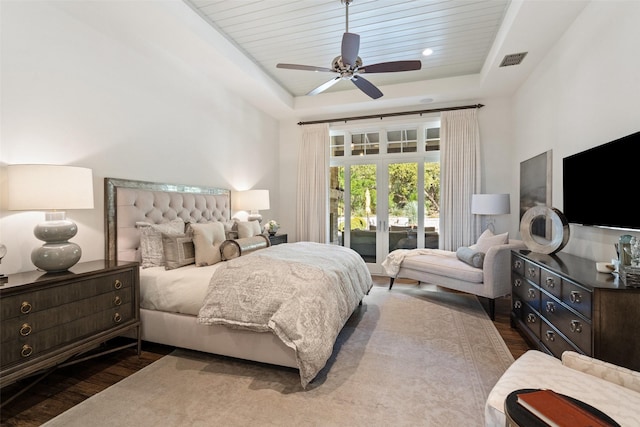 bedroom featuring access to exterior, hardwood / wood-style flooring, a raised ceiling, and ceiling fan