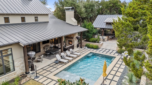 view of swimming pool with an outdoor fireplace, exterior bar, a gazebo, and a patio area