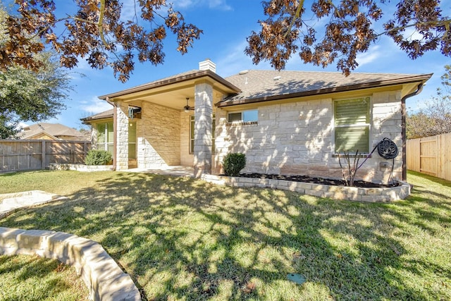 rear view of property featuring ceiling fan and a lawn