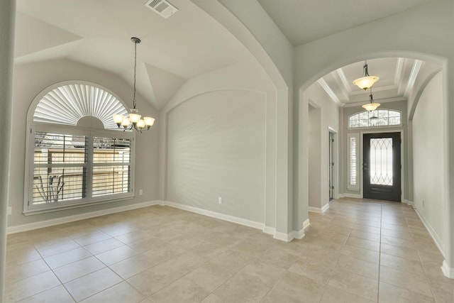 tiled foyer entrance with ornamental molding and a chandelier