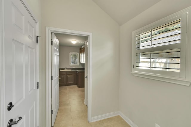 hall with lofted ceiling, sink, and light tile patterned flooring