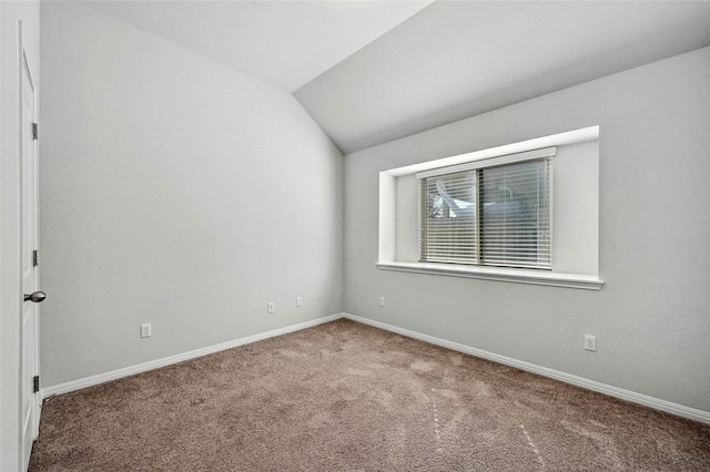 carpeted empty room featuring vaulted ceiling