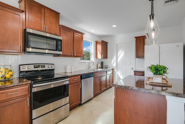 kitchen with sink, decorative light fixtures, dark stone countertops, stainless steel appliances, and backsplash