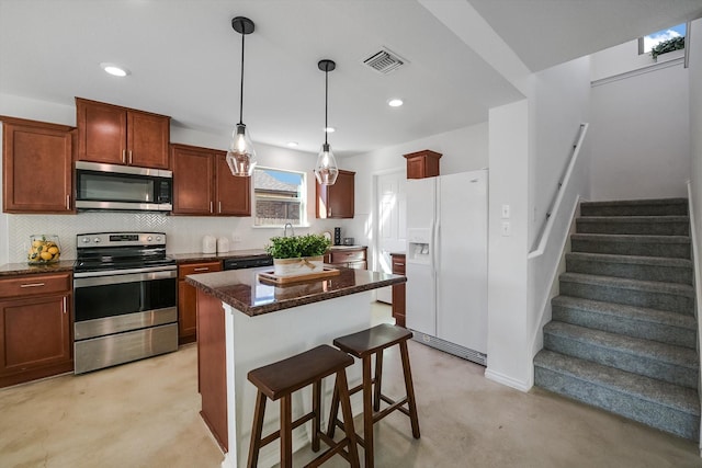 kitchen featuring a center island, hanging light fixtures, dark stone countertops, a kitchen breakfast bar, and stainless steel appliances