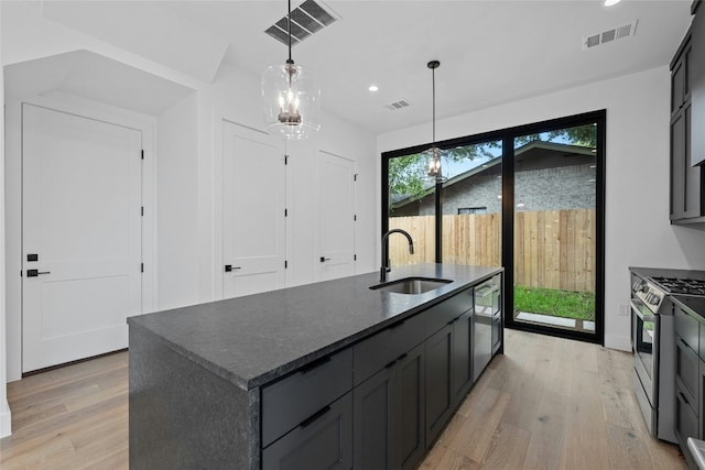 2010 Gathright Unit B, Austin, TX 78704 - kitchen featuring stainless steel range with gas stovetop, light wood finished floors, recessed lighting, a center island with sink, and hanging light fixtures
