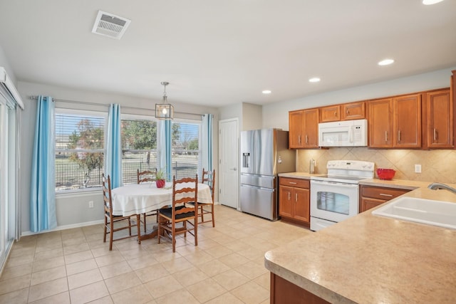 kitchen featuring pendant lighting, sink, white appliances, light tile patterned flooring, and decorative backsplash