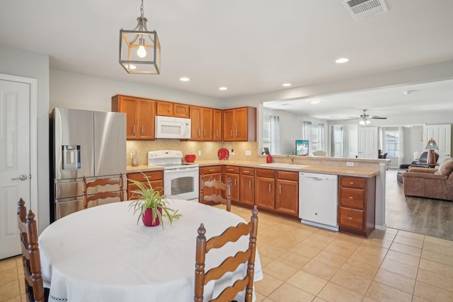 kitchen with sink, white appliances, light tile patterned floors, hanging light fixtures, and backsplash