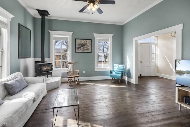 living room featuring dark wood-type flooring, ornamental molding, ceiling fan, and a wood stove