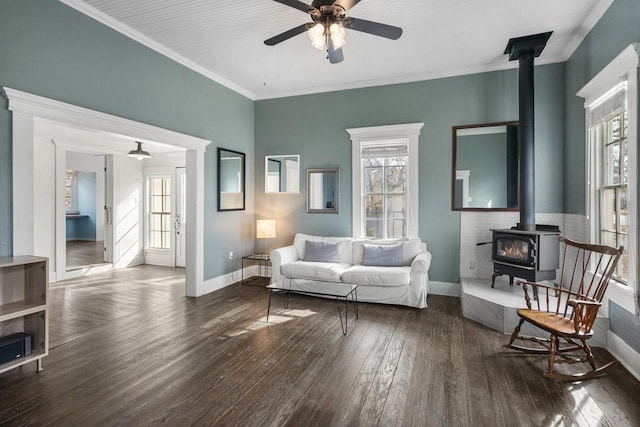 living room with hardwood / wood-style flooring, crown molding, a wood stove, and ceiling fan