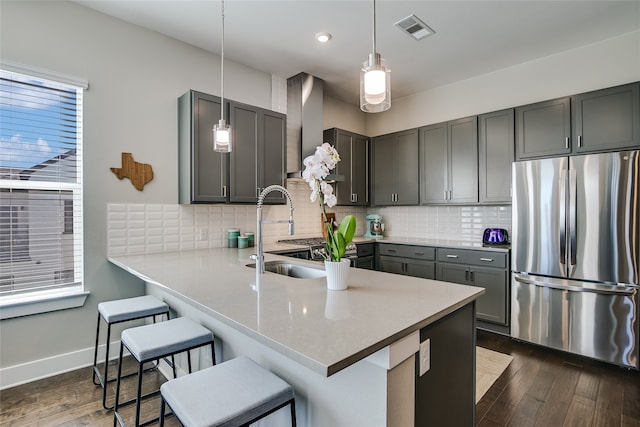 kitchen with wall chimney exhaust hood, decorative light fixtures, stainless steel refrigerator, kitchen peninsula, and gray cabinets