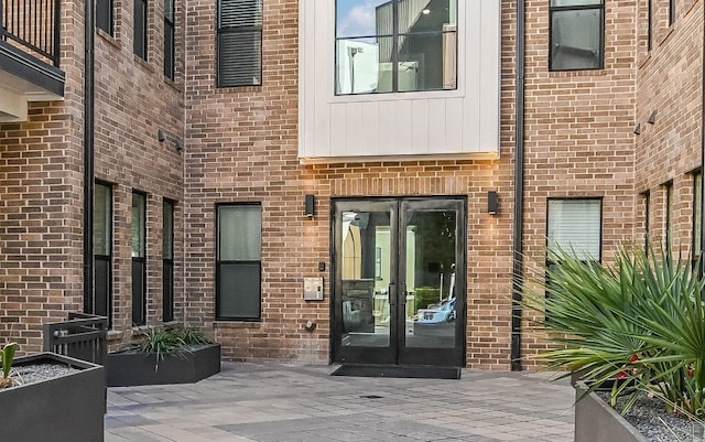 property entrance featuring french doors and brick siding