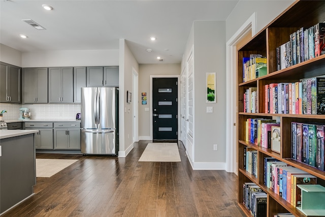 kitchen featuring stainless steel refrigerator, dark wood-type flooring, decorative backsplash, and gray cabinetry