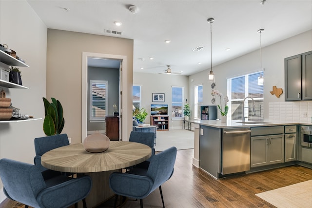 kitchen with dark hardwood / wood-style floors, decorative light fixtures, tasteful backsplash, dishwasher, and sink