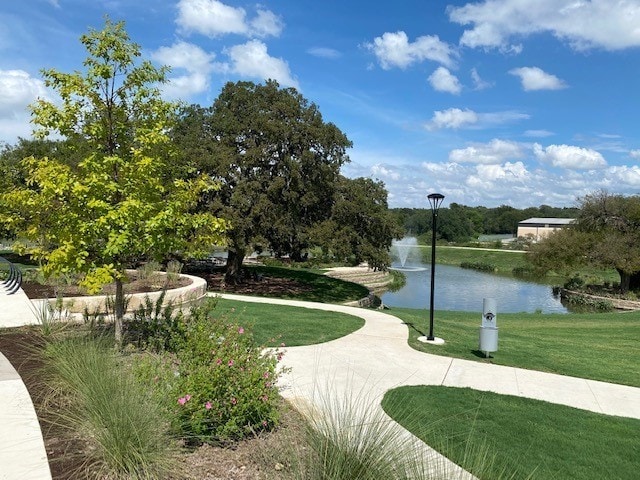 view of home's community with a water view and a lawn