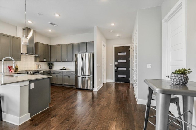 kitchen with a sink, tasteful backsplash, wall chimney exhaust hood, visible vents, and freestanding refrigerator