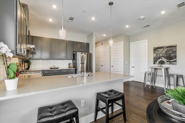 kitchen featuring a peninsula, a sink, freestanding refrigerator, and visible vents