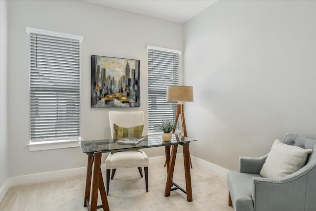 office space featuring plenty of natural light, baseboards, and light carpet